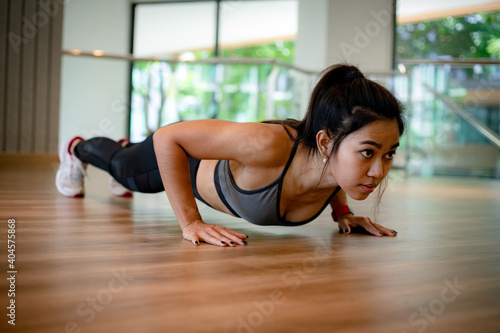 young Asian woman doing push ups in the gym