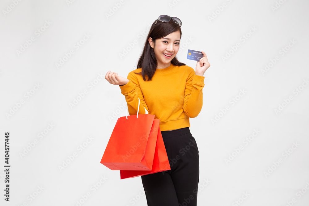 Young Asian woman holding credit card and red shopping bags isolated on white background Young Asian woman holding credit card and red shopping bags isolated on white background