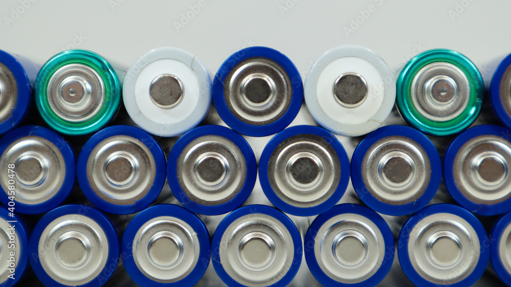 Lots of AA and AAA alkaline batteries on a white background. Ecological recycling concept. The terminals of the disposable batteries are close together and form a beautiful backdrop. Energy source. Lots of AA and AAA alkaline batteries on a white background. Ecological recycling concept. The terminals of the disposable batteries are close together and form a beautiful backdrop. Energy source.