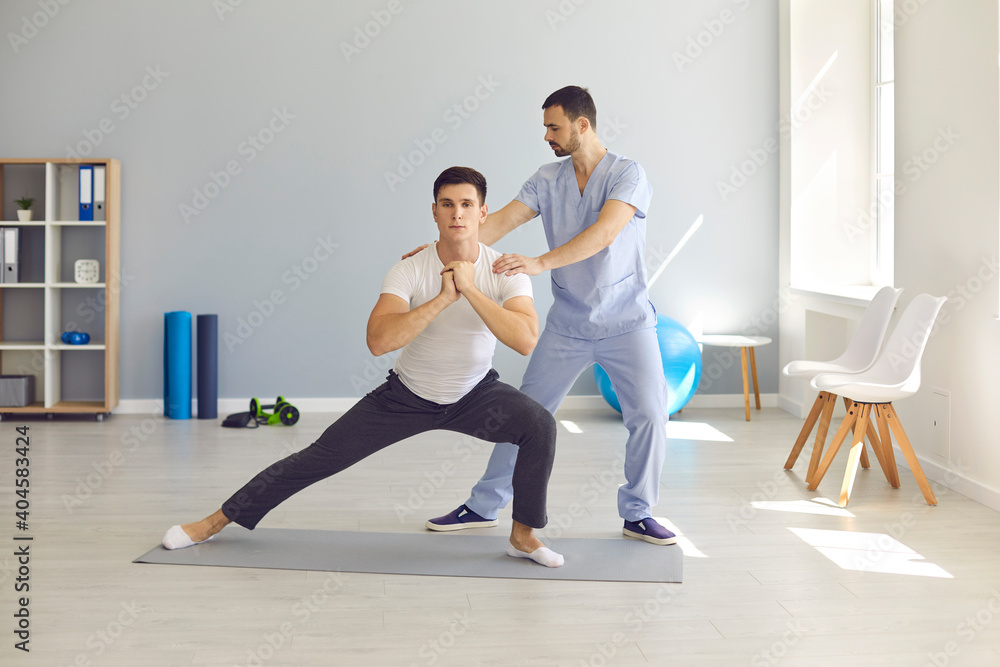 Physiotherapist helping patient do side lunges to develop balance, stability and strength Physiotherapist helping patient do side lunges to develop balance, stability and strength