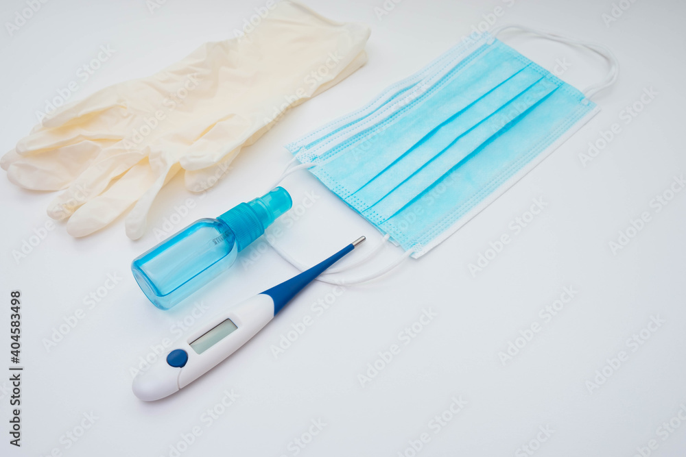 thermometer, face mask, gloves and antiseptic on a white background thermometer, face mask, gloves and antiseptic on a white background