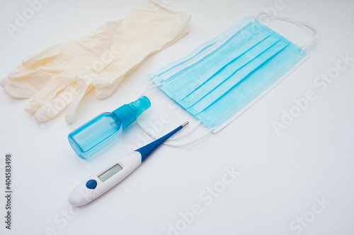 thermometer  face mask  gloves and antiseptic on a white background