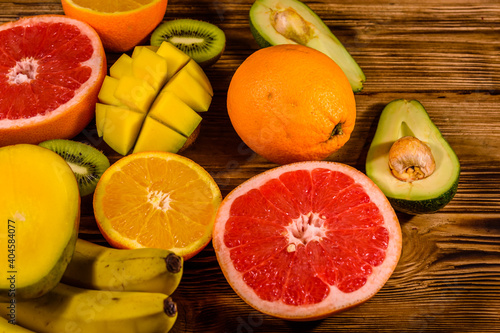 Still life with exotic fruits. Bananas  mango  oranges  avocado  grapefruit and kiwi fruits on wooden table