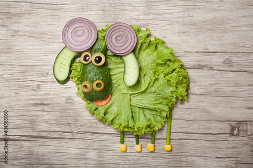 Fun food idea for kids. Ram made of vegetables on orange plate. Horizontal wooden background.