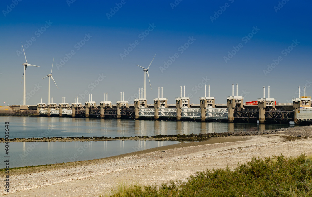 Netherlands, August 2019. In Zeeland, wind farms are the setting for the immense dam that governs the flow of sea waters, securing the territory. Netherlands, August 2019. In Zeeland, wind farms are the setting for the immense dam that governs the flow of sea waters, securing the territory.