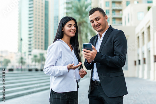 Business woman and businessman looking at mobile phone in the city serious talking and surf on internet by mobile phone