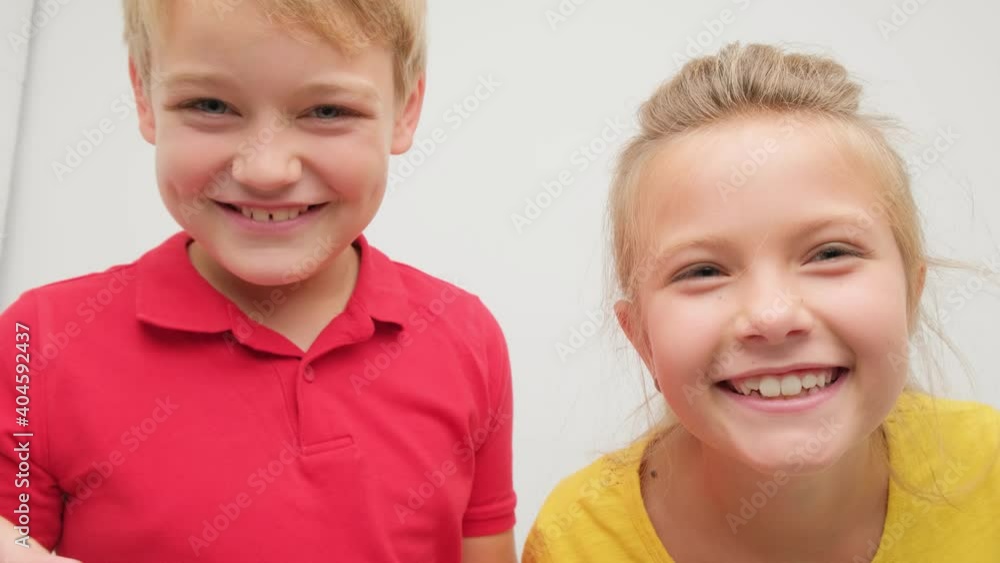 Boy and girl posing for the camera in the studio on a white background. Children fool around and frolic. Boy and girl posing for the camera in the studio on a white background. Children fool around and frolic.
