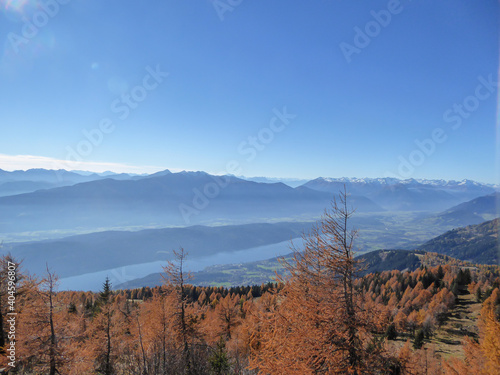 A distant view on the Millstaetter lake in Austrian Alps. Sunny and bright autumn day. The lake is surrounded by high Alps. Unspoiled landscape. Flora is turning golden. Serenity and calmness