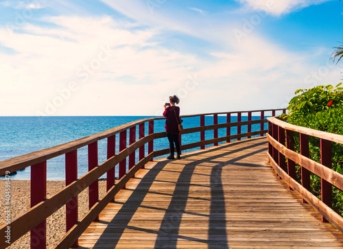 Fotografía Chica joven haciendo fotografias con el movilal mar  desde la senda litoral de M