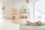 Cozy interior of a bright Balinese-style apartment with white walls, bamboo chair, big white sofa and decorations