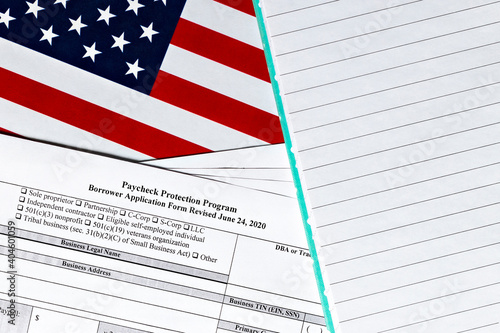 close-up of paycheck protection program borrower application form revised topview, on a background of United States flag. paycheck protection program new round.