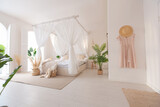 Cozy interior of a bright Balinese-style apartment with white walls, bamboo furniture. bed room with night lights, bed with balanchin and large windows