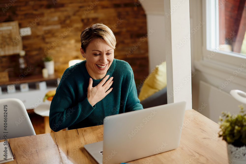 Happy woman laughing while having video call over laptop at home. Happy woman laughing while having video call over laptop at home.