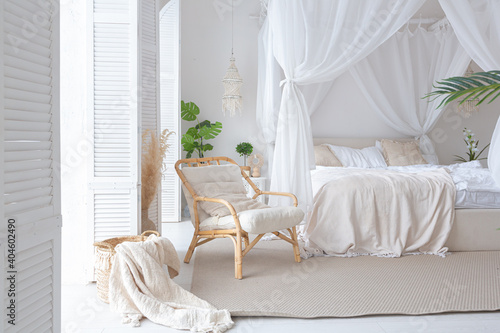 Cozy interior of a bright Balinese-style apartment with white walls  bamboo furniture. bed room with night lights  bed with balanchin and large windows