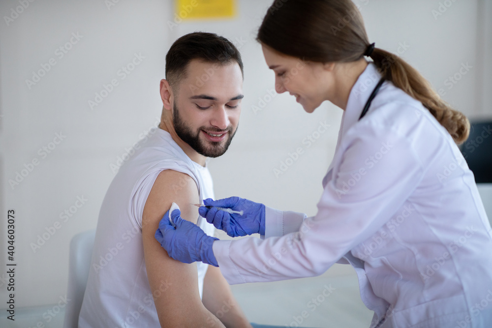 Obraz premium General practitioner vaccinating young male patient, making covid-19 vaccine injection at clinic