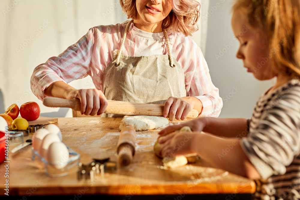 woman and child girl cooking together in kitchen, young mom teaches cute kid girl kneading dough for domestic pie preparing surprise for family woman and child girl cooking together in kitchen, young mom teaches cute kid girl kneading dough for domestic pie preparing surprise for family