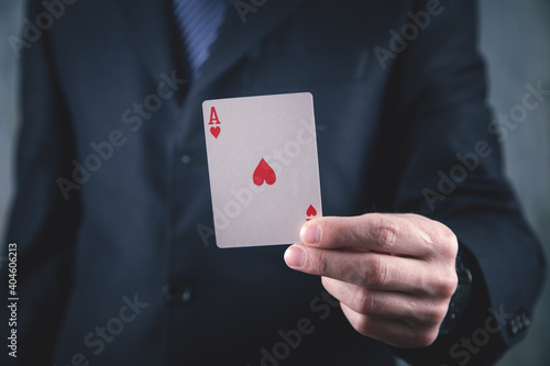 Businessman in suit holding playing card.
