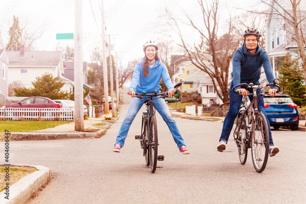 Fototapeta premium Husbands and wife ride a bicycle fun lifting legs smile on urban American street