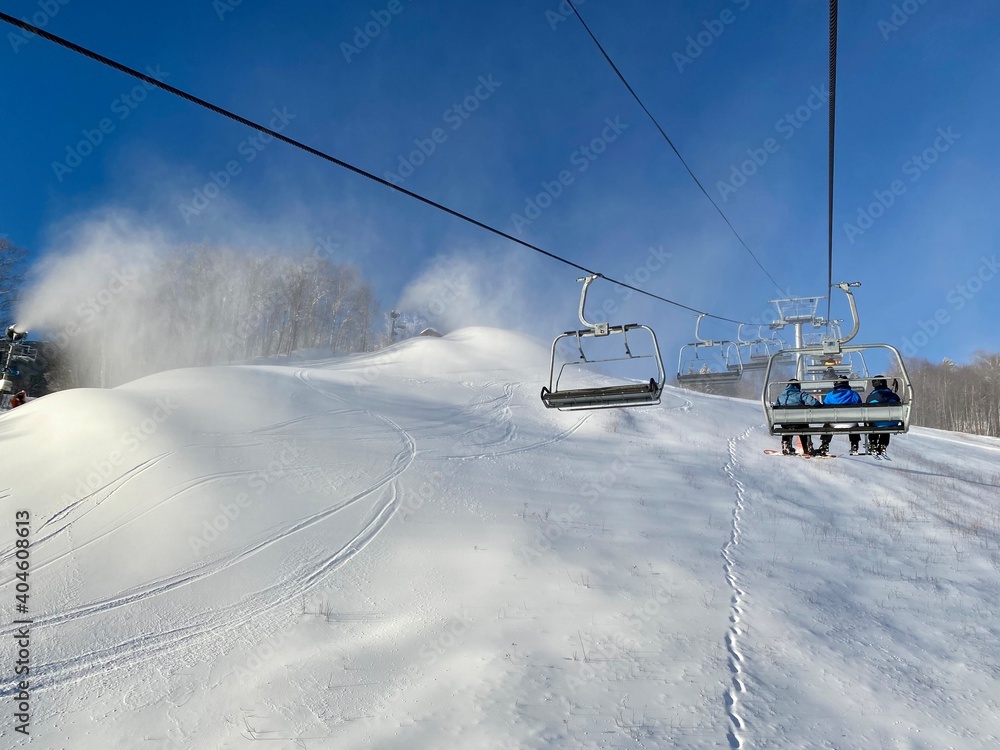Obraz premium Chairlift going up during snowmaking in progress at Stowe ski resort, VT USA