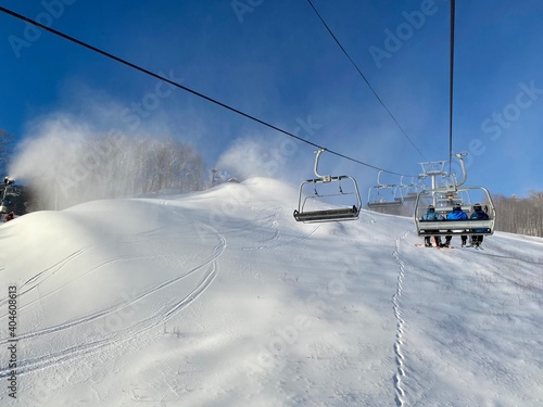 Chairlift going up during snowmaking in progress at Stowe ski resort, VT USA