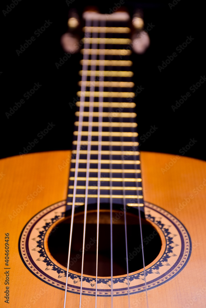 Close-up of an acoustic guitar lies on its side. Perspective frame with highly blurred background Close-up of an acoustic guitar lies on its side. Perspective frame with highly blurred background