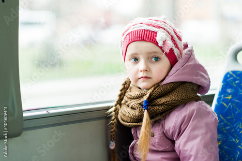 Little beautiful girl sitting on the bus by the window. Lost child.