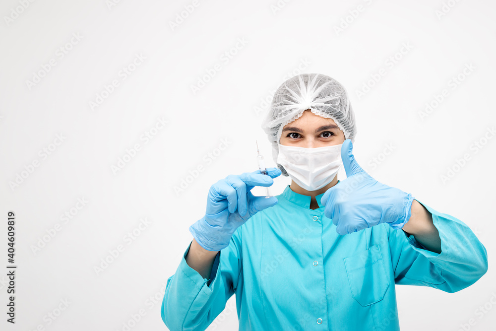 Positive medical worker in protective clothing,gloves and mask holding a syringe and showing the thumb up sign.Medicine and healthcare concept.Coronavirus vaccination concept. Positive medical worker in protective clothing,gloves and mask holding a syringe and showing the thumb up sign.Medicine and healthcare concept.Coronavirus vaccination concept.