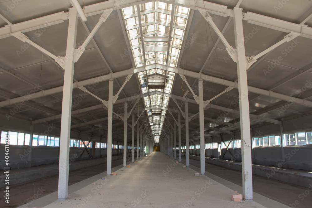 Inside the production building under construction. Metal frame of the building with a sandwich panel of insulation on the wall. Engineering solutions in modern building construction Inside the production building under construction. Metal frame of the building with a sandwich panel of insulation on the wall. Engineering solutions in modern building construction