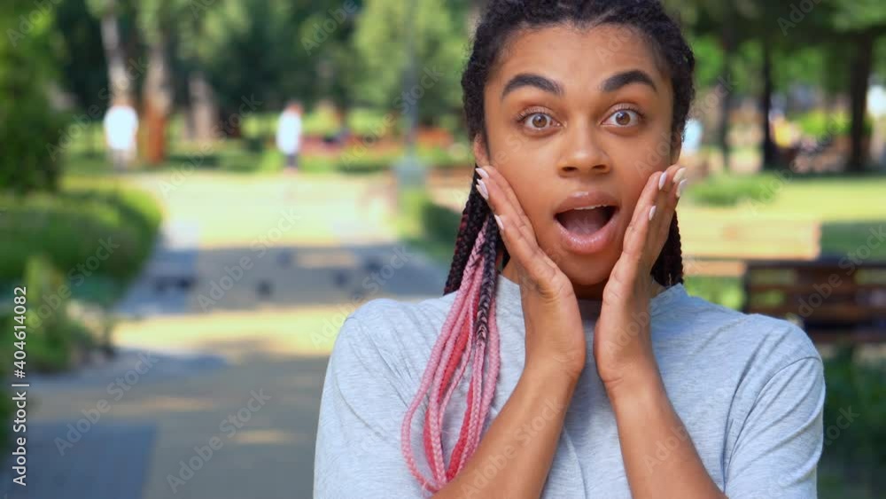 portrait young african american woman looking camera show surprise happy smiling summer landscape in city park portrait young african american woman looking camera show surprise happy smiling summer landscape in city park