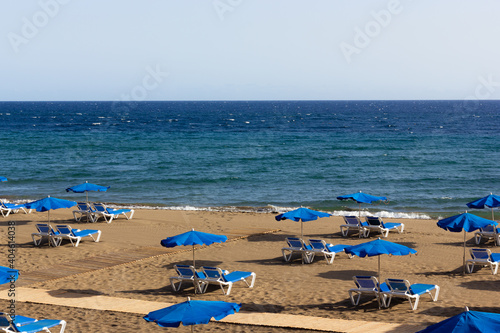 Blue hammocks and umbrellas on empty beach in Puerto del Carmen, Lanzarote. Tourism abscence, pandemic crisis, economy decline concepts photo