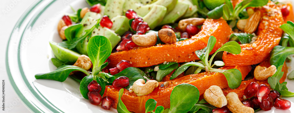Fresh vegetable salad with lambs lettuce, baked butternut squash or pumpkin, avocado, pomegranate, cashew and almond nuts. Healthy vegetarian food concept. Banner Fresh vegetable salad with lambs lettuce, baked butternut squash or pumpkin, avocado, pomegranate, cashew and almond nuts. Healthy vegetarian food concept. Banner