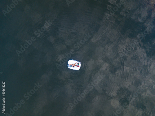 Beautiful couple sleeping on mattress with white bedding floating in water. View from drone