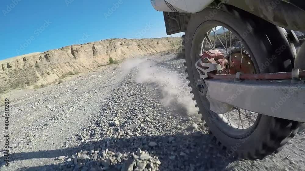 Side view of wheel off road motorcycle starting movement. Dry ground or dust flying around. Side view of wheel off road motorcycle starting movement. Dry ground or dust flying around.