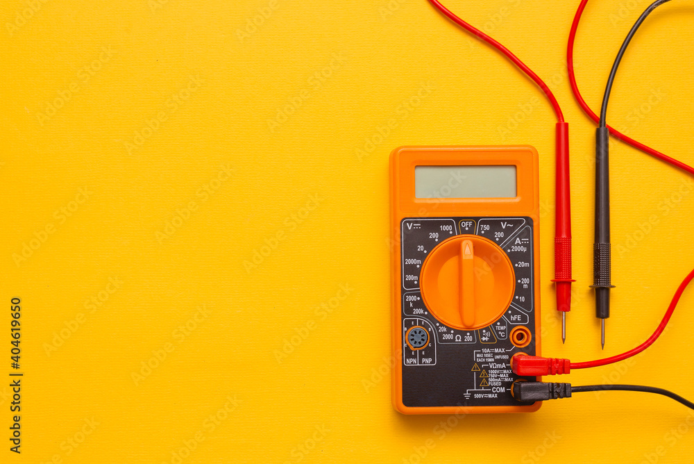 Electric multimeter on the yellow background with copy space. Stock