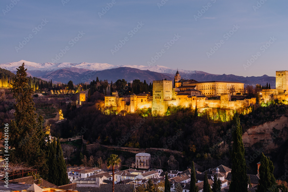 Alhambra muslim palace in Granada at night with buildings below from San Nicolas lookout