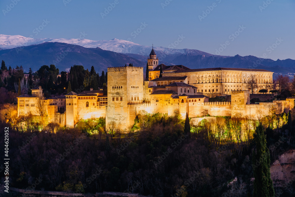 Alhambra palace in Granada at night with a little of snow in the mountains in the back from San Nicolas lookout