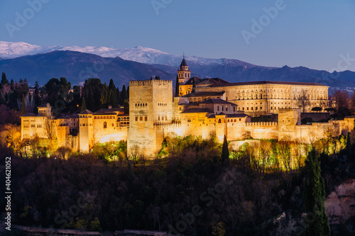 Alhambra palace in Granada at night with a little of snow in the mountains in the back from San Nicolas lookout