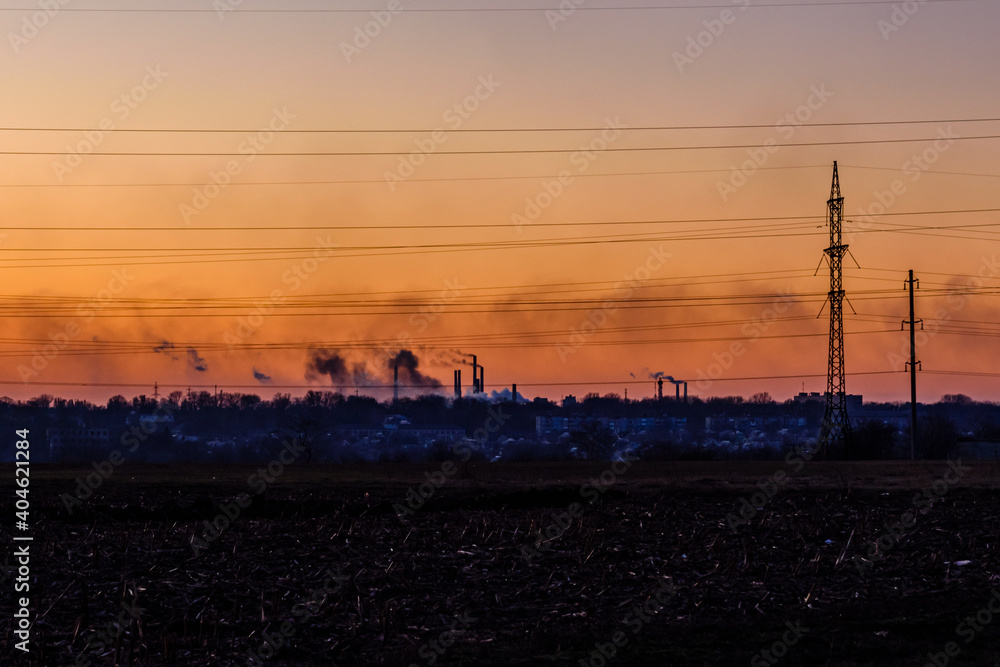 View on smoke pipes of the factory at sunset
