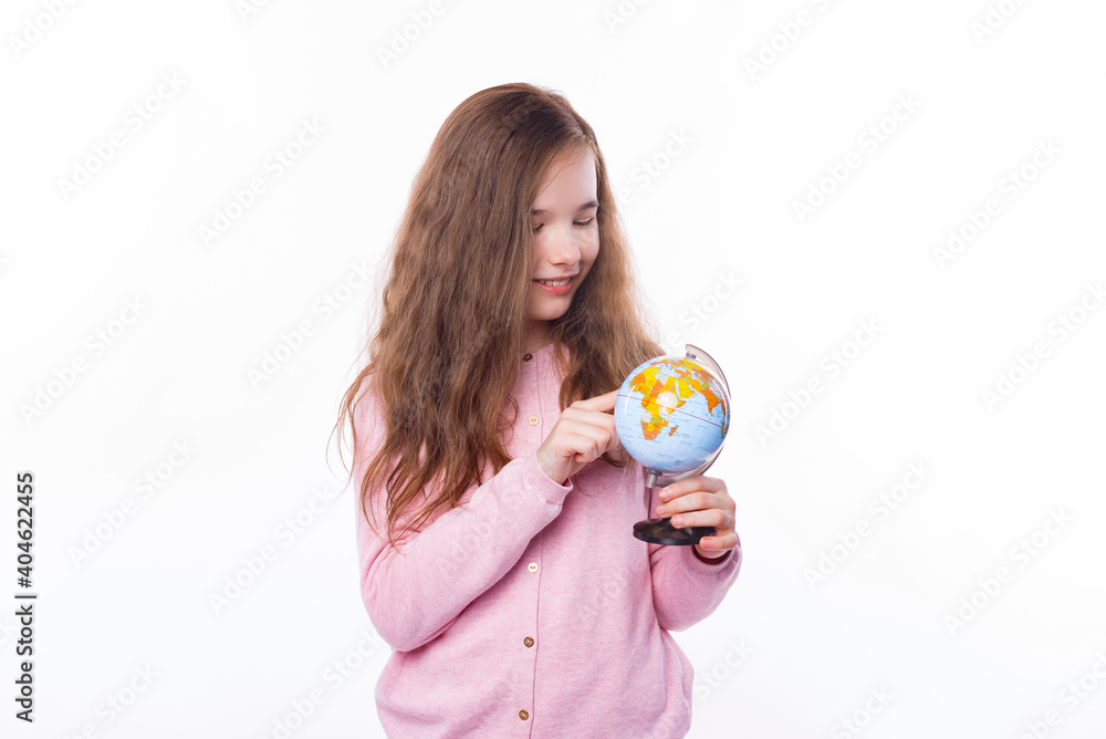 Photo of young girl standing over white background and pointing on little globe for other destination. Photo of young girl standing over white background and pointing on little globe for other destination.