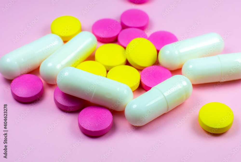 Colored pills and tablets on pink background. Close up. Medical treatment concept. Colored pills and tablets on pink background. Close up. Medical treatment concept.
