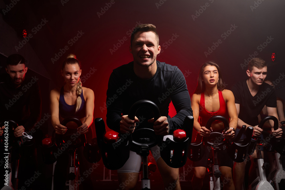 Fototapeta premium sportsman diligently riding an exercise bike in gym, the guy is exercising on a stationary bike