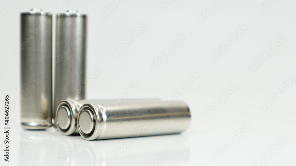 AA alkaline rechargeable batteries on white glossy background with reflection. Close up four empty batteries with copy space. AA alkaline rechargeable batteries on white glossy background with reflection. Close up four empty batteries with copy space.