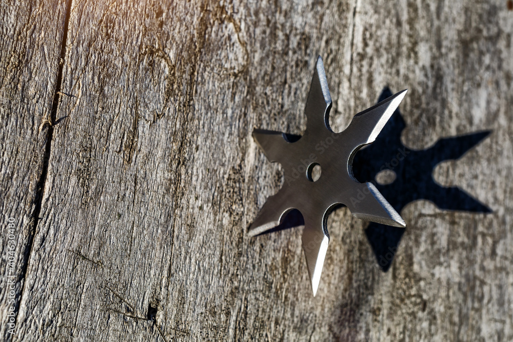 Φωτογραφία Shuriken (throwing star), traditional japanese ninja cold weapon stuck in wooden background,Silver shuriken with star shape