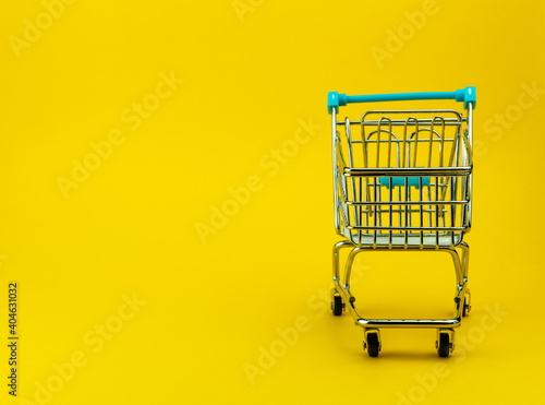 Empty shopping cart in yellow background with copyspace. retail store