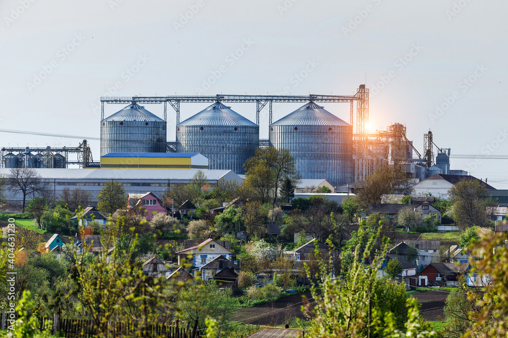 Obraz premium Agricultural Silos. Storage and drying of grains, wheat, corn, soy, sunflower against the blue sky with white clouds.Storage of the crop
