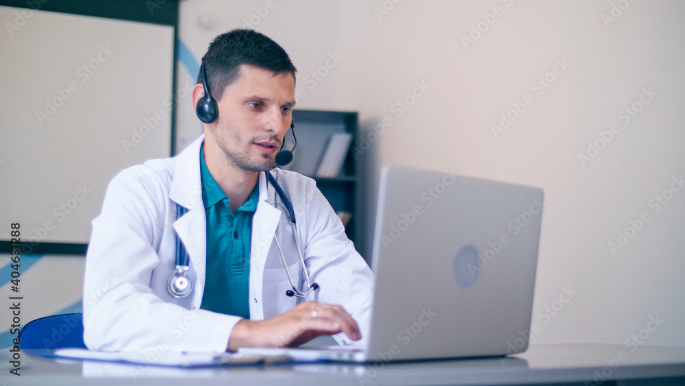 Friendly Male Doctor in White Medical Coat With Headphones Making Conference Call on Laptop.Remote Consulting Patient Online From Healthcare Hospital. Telemedicine. Friendly Male Doctor in White Medical Coat With Headphones Making Conference Call on Laptop.Remote Consulting Patient Online From Healthcare Hospital. Telemedicine.