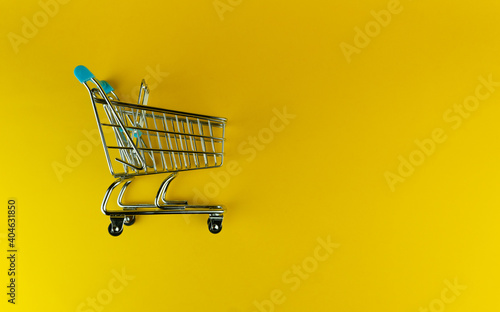 Side view of an empty shopping cart isolated on yellow background with copyspace