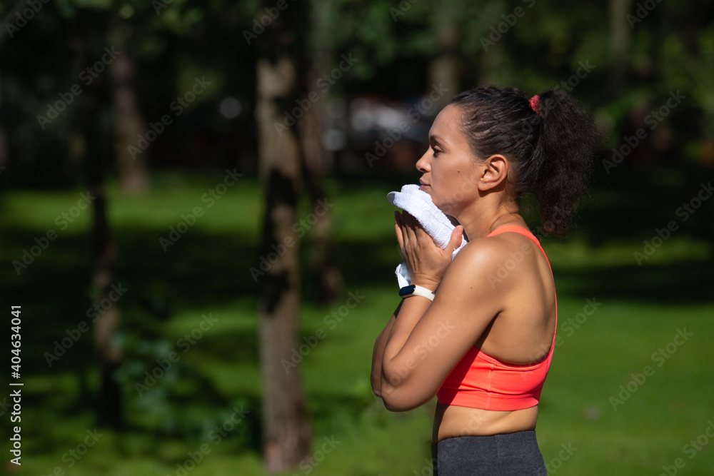 Side portrait of tired young woman wiping her sweat after exercise workout Side portrait of tired young woman wiping her sweat after exercise workout