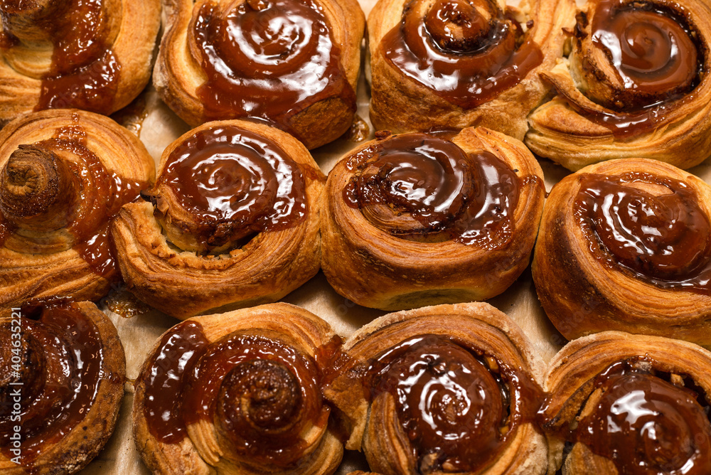 Homemade cinnamon buns with spices and caramel on parchment paper. Homemade cinnamon buns with spices and caramel on parchment paper.