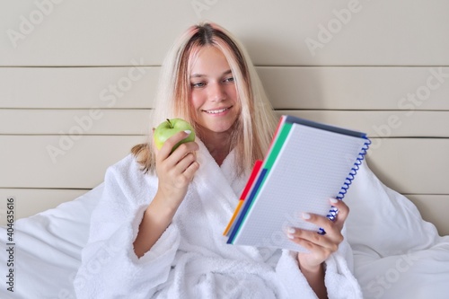 Teenager girl student with green apple and school notebook